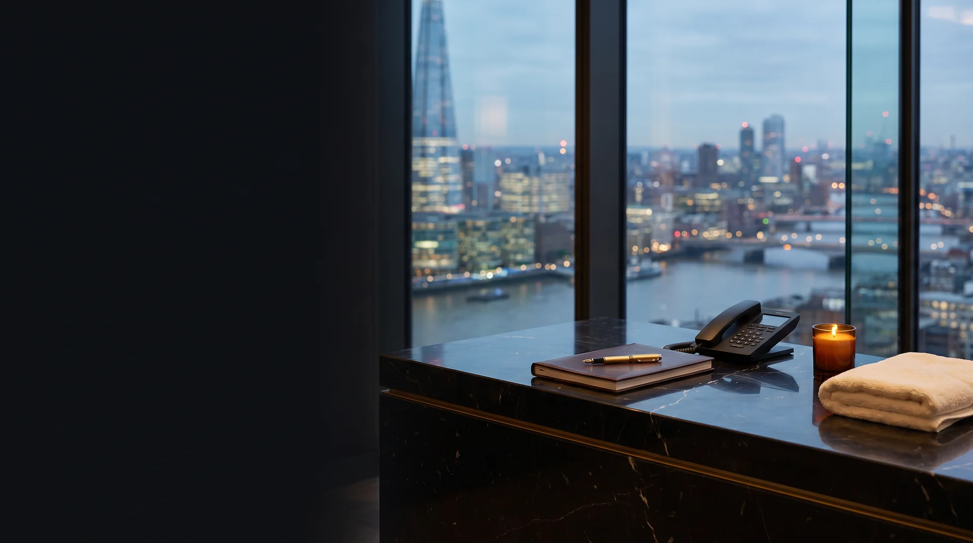 Black marble concierge desk with an appointment book, telephone, candle and London skyline